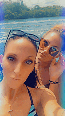 two women wearing sunglasses and a cross necklace pose for a selfie