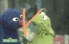 kermit the frog and elmo from sesame street are standing next to each other and kissing .