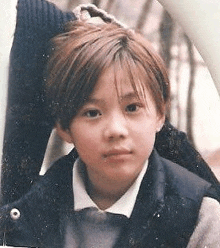 a young girl with short hair is wearing a school uniform .