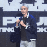 a man in a blue jacket is holding a microphone in front of a screen that says pj .