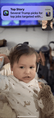 a baby is being held by a woman on a video call with a notification that says top story