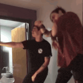 a man in a black t-shirt with the letter s on it is dancing with another man in a red shirt