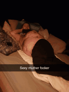 a man with a beard is laying on a bed with a caption that says sexy mother focker