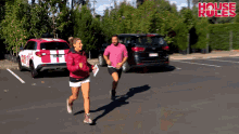 a man and a woman are running in a parking lot with the words house rules written on the bottom