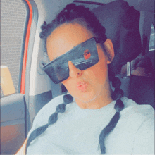 a woman wearing sunglasses is blowing a kiss in a car