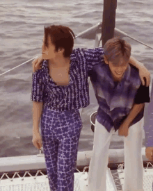 two men are standing on a boat with their arms around each other 's shoulders