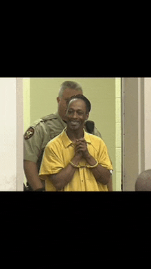 a man in a yellow shirt is smiling while being escorted by two police officers