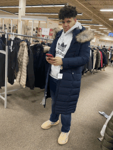 a man wearing a blue adidas jacket stands in a store