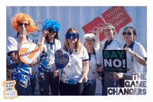 a group of women are posing for a picture and one of them is holding a sign that says say no