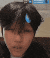 a close up of a person 's face with a blue drop of water on their forehead