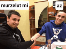 two men shaking hands in front of a sign that says " murzelut mi "