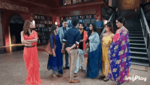 a group of people standing next to each other in a room with a staircase in the background .