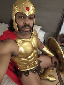 a man dressed as a gladiator with a red cape and gold armor