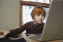 a young boy is looking at a laptop computer with a surprised look on his face