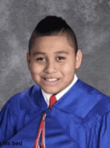 a boy in a blue cap and gown is smiling