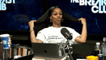 a woman wearing a shirt that says diary of lauryn hill holds her hair in front of a microphone