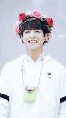 a young man wearing a flower crown is smiling and wearing a white shirt .