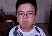 a young boy wearing glasses and a white shirt is making a face