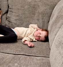 a baby is laying on a couch with his eyes closed