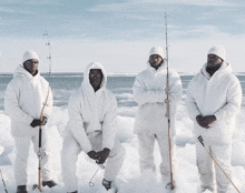 four men standing in the snow with fishing rods in their hands