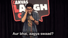 a man holding a microphone in front of a canvas laugh sign