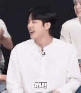 a man in a white shirt is laughing while sitting next to a group of people .