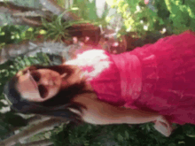 a woman wearing sunglasses and a pink dress is laying down