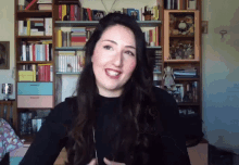 a woman is smiling in front of a bookshelf that has a book titled " a brief history of the world " on it