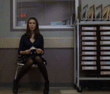 a woman sits on a chair in front of a cart of binders with one labeled ' a ' on it