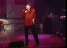 a man in a red jacket singing into a microphone