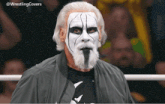 a man with white face paint and a beard is wearing a black shirt with a shark on it
