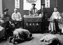 a group of men are kneeling in front of a table with chinese characters on it