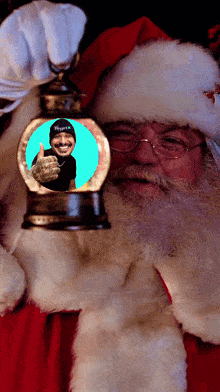 santa claus is holding a snow globe with a picture of him inside