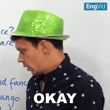 a man wearing a green hat with the word okay on it
