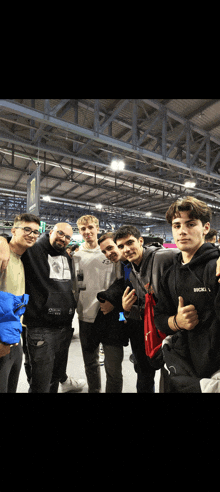 a group of young men are posing for a picture and one of them is wearing a black hoodie that says mickey mouse on the front