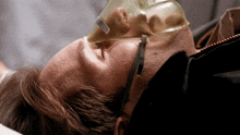 a man wearing an oxygen mask is laying down with his eyes closed