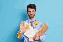 a man with sticky notes on his shirt and tie is holding a folder and a piece of paper