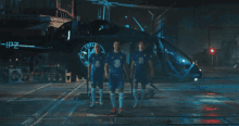 three soccer players are standing in front of a helicopter that says chelsea