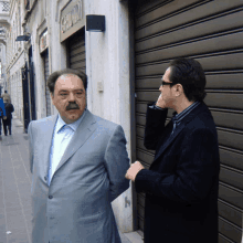 two men are standing in front of a building that says giorgio