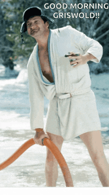 a man in a bathrobe is holding a vacuum hose with the words good morning griswold written above him