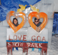 a man and a woman are posing for a photo in front of a sign that says love goa snow park