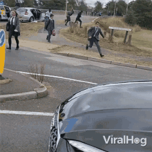 a man in a suit is running across a street next to a car with viralhog written on the hood