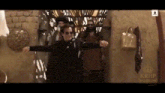 a man in a black suit and sunglasses is dancing in front of a group of men .