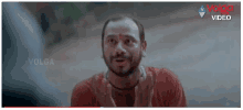 a man with a beard and a red shirt is making a funny face in a movie .