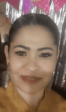 a close up of a woman 's face with a yellow shirt and earrings