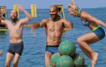 a man and two women are jumping in the water with a sign that says ' o ' on it in the background