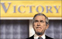 a man stands in front of a banner that says victory