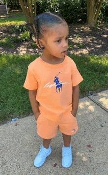 a little boy wearing an orange shirt with a blue polo on it