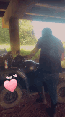 a man in a black shirt is standing next to a four wheeler that says may 28