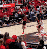 a basketball game is being played in front of a crowd with a state farm sign in the background .